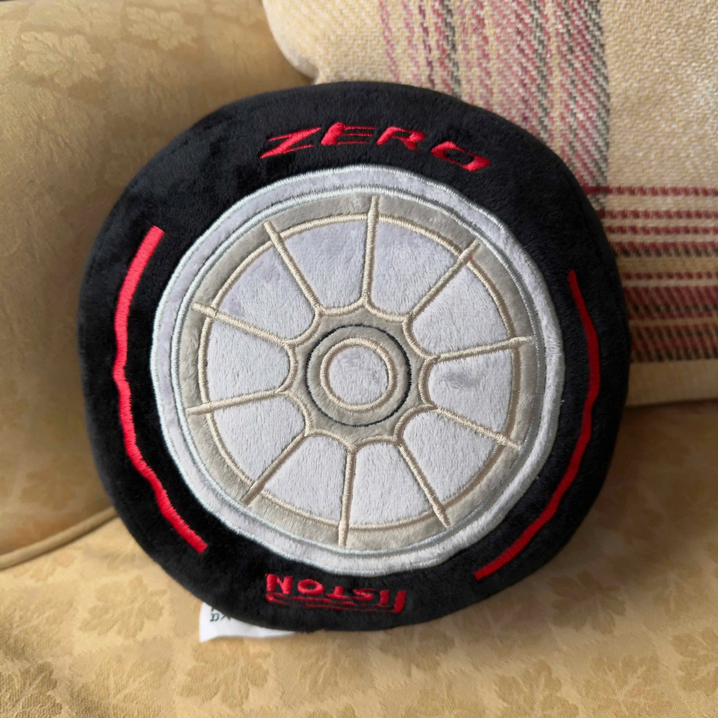 Formula 1 Race Tire Plush Toy shown on seat with cushion on background