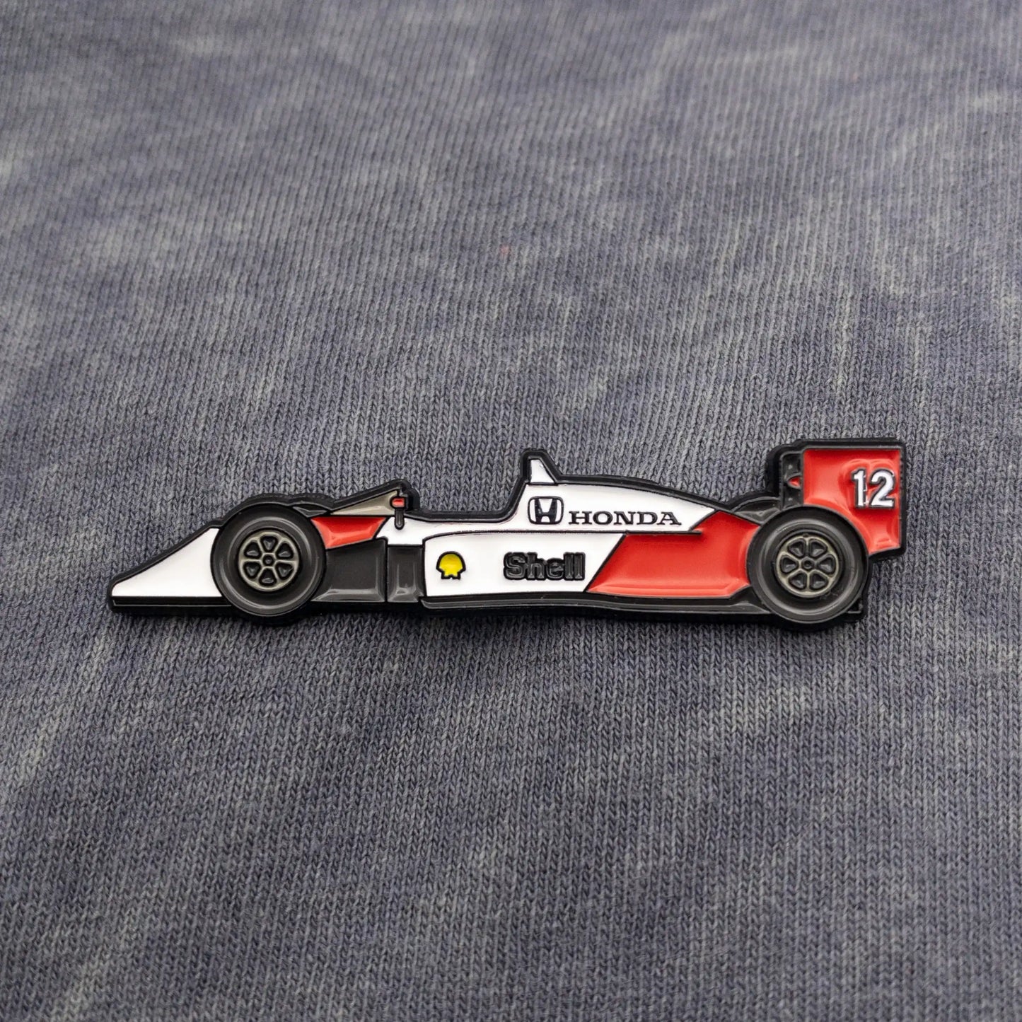 McLaren MP4/4 Formula One Car Enamel Pin shown on grey fabric