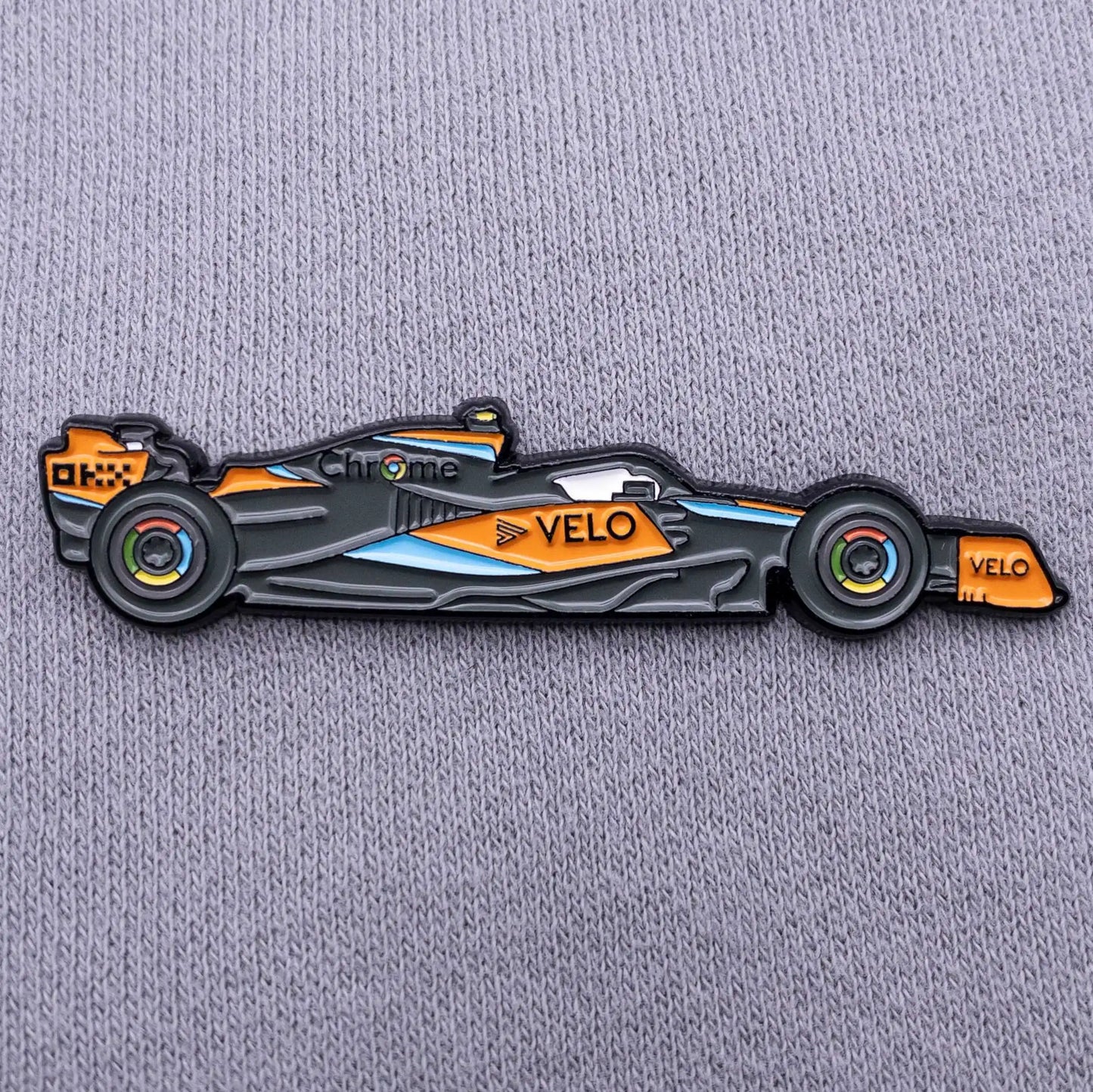 McLaren MCL60 Formula One Car Enamel Pin shown on grey clothes