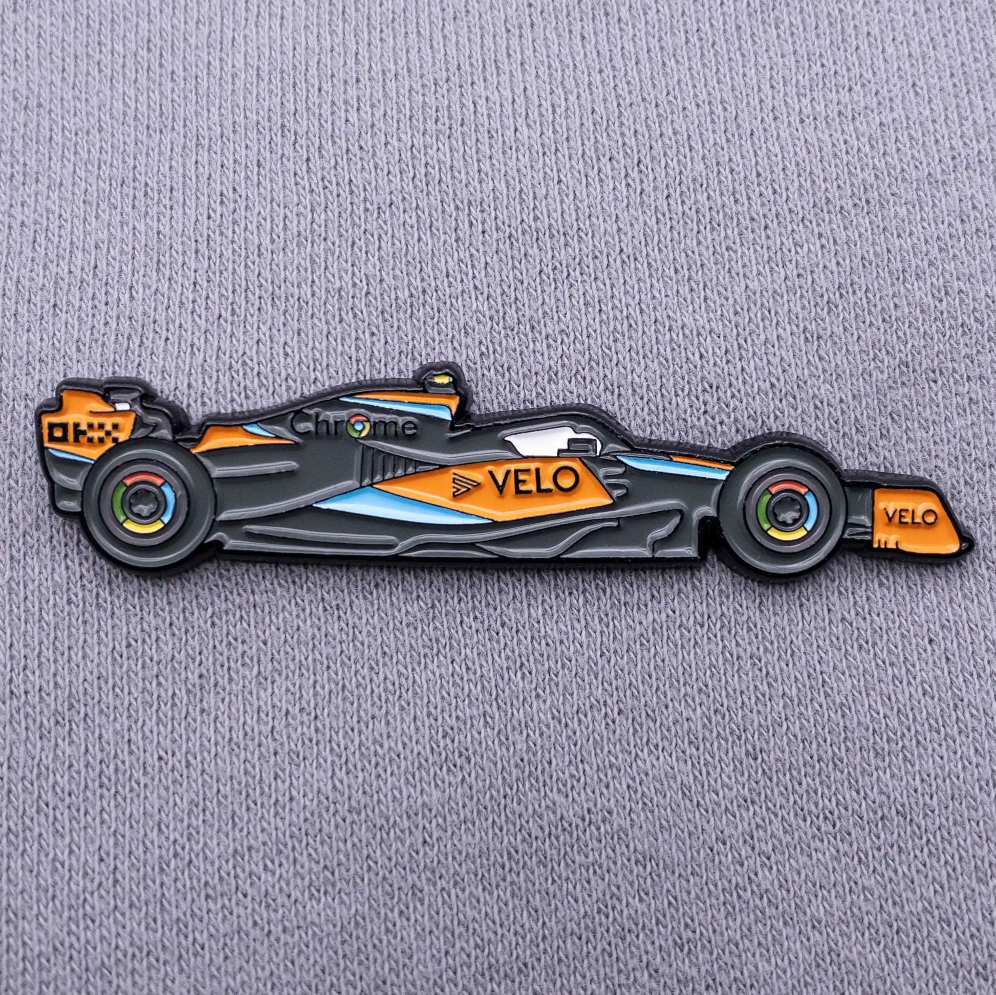 McLaren MCL60 Formula One Car Enamel Pin shown on grey clothes