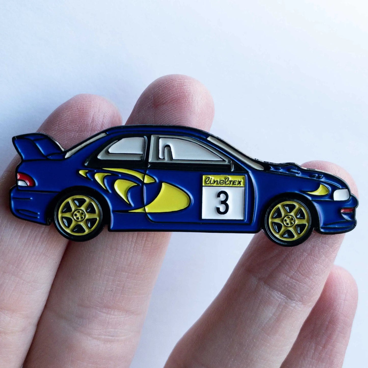 Subaru Impreza WRC98 Rally Car Enamel Pin shown on hand