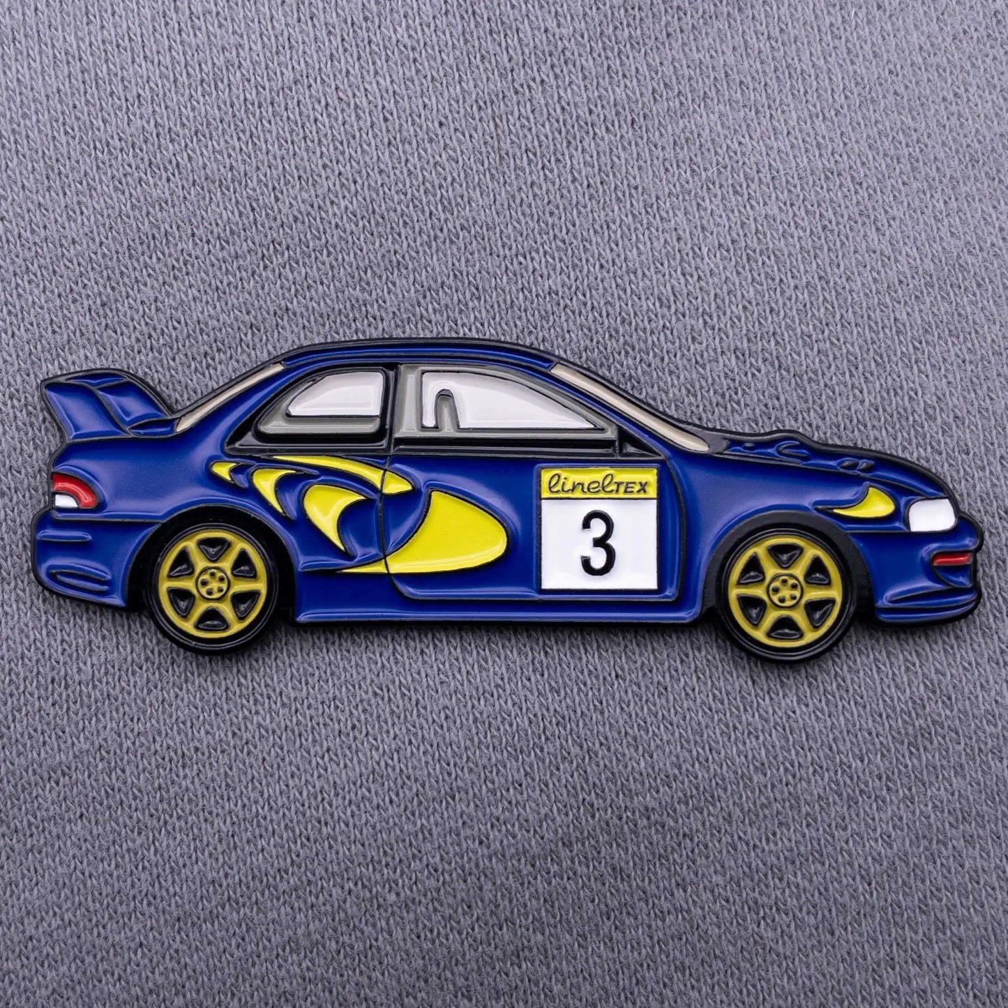Subaru Impreza WRC98 Rally Car Enamel Pin shown on grey clothes