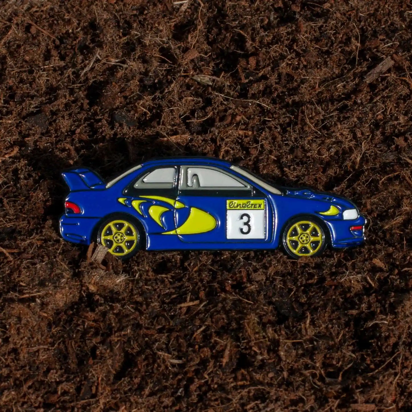 Subaru Impreza WRC98 Rally Car Enamel Pin shown on dirt background