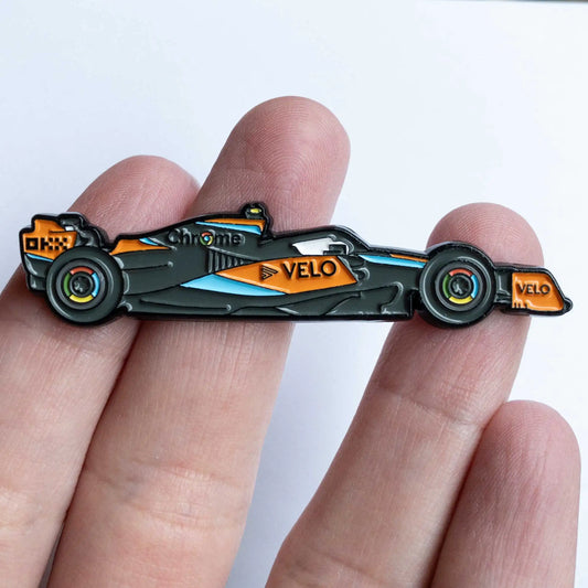 McLaren MCL60 Formula One Car Enamel Pin shown on hand