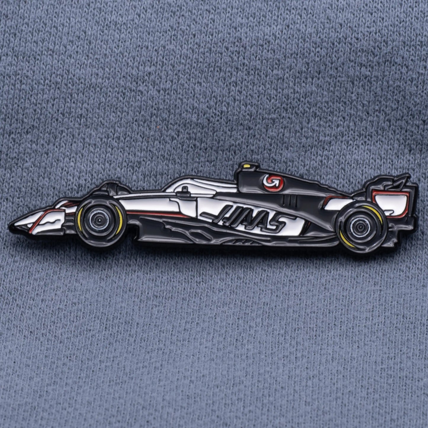 Haas VF-25 Formula One Car Enamel Pin shown on grey cloth