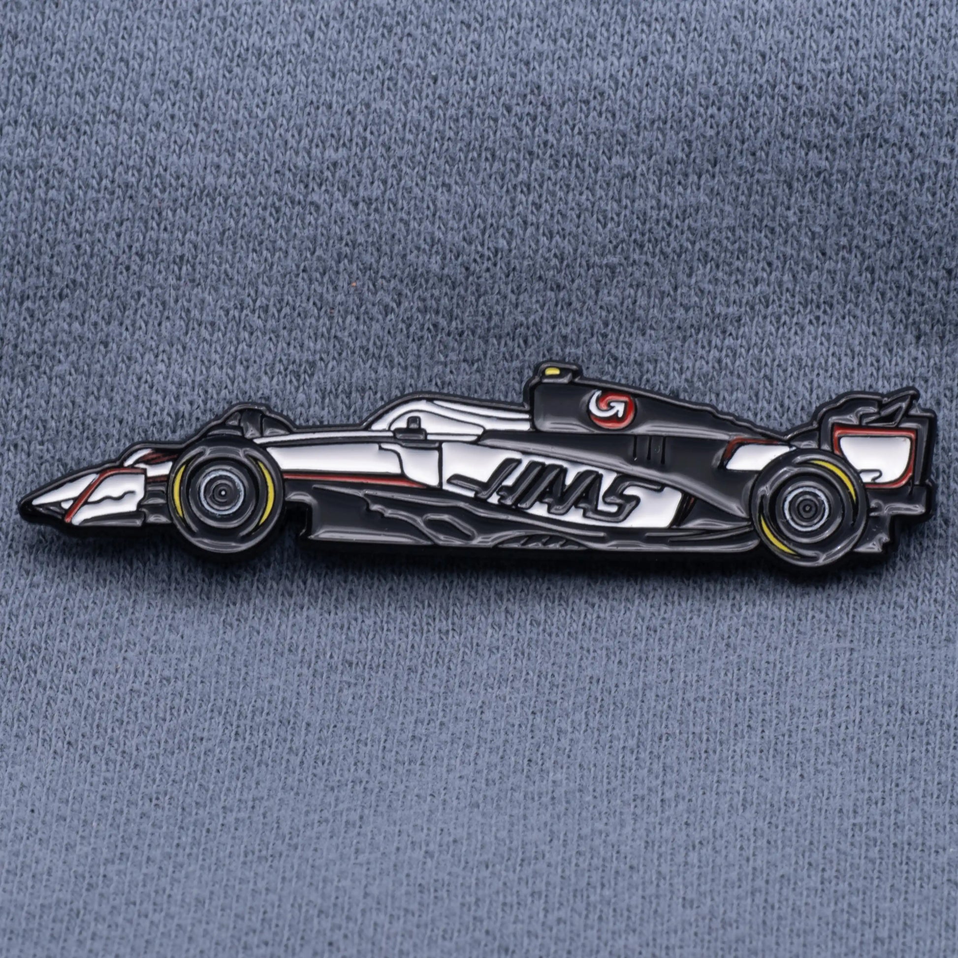 Haas VF-25 Formula One Car Enamel Pin shown on grey cloth