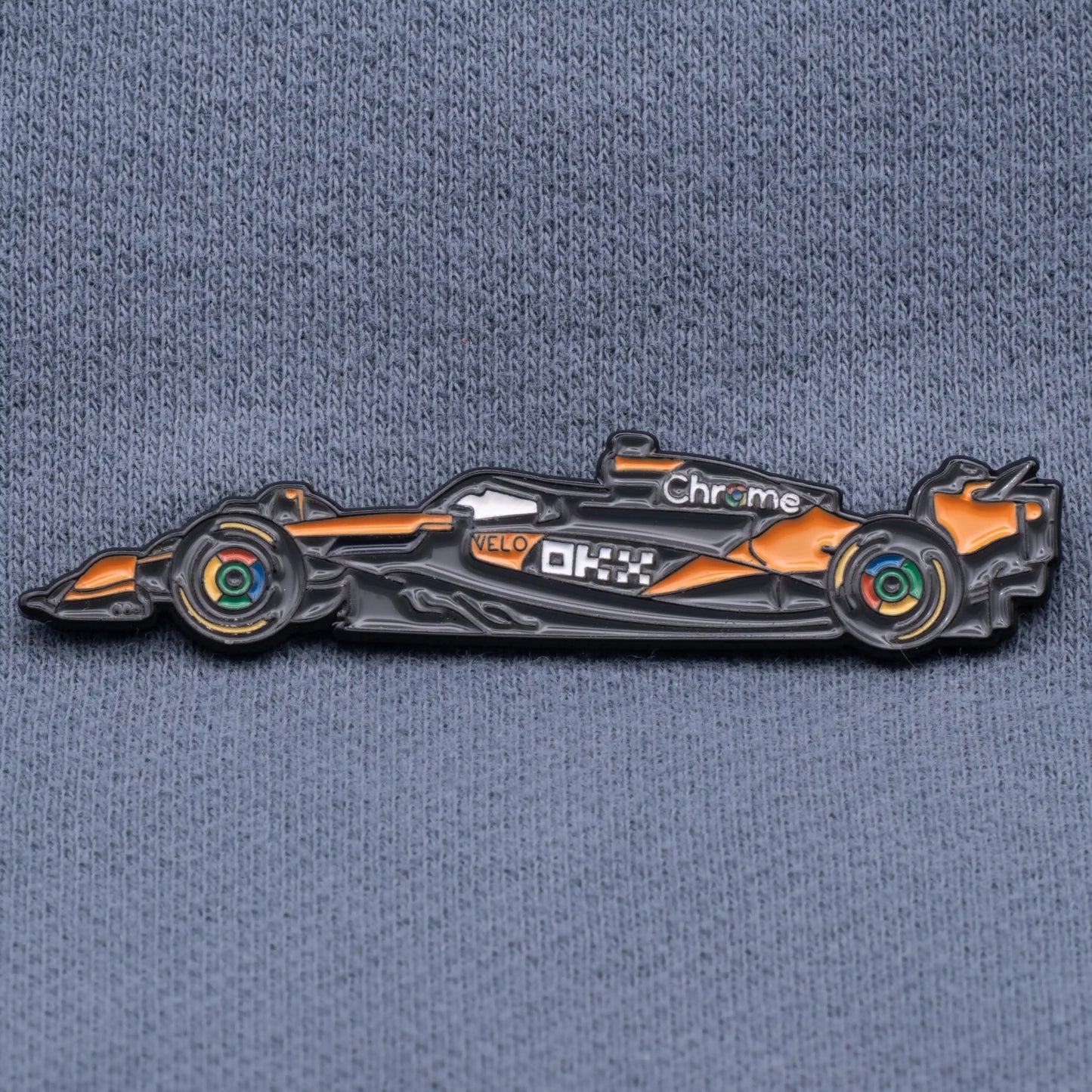 McLaren MCL39 Formula One Car Enamel Pin shown on grey cloth