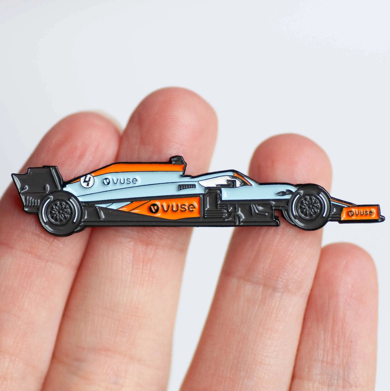 McLaren MCL35M Gulf Livery Formula One Car Enamel Pin shown on hand