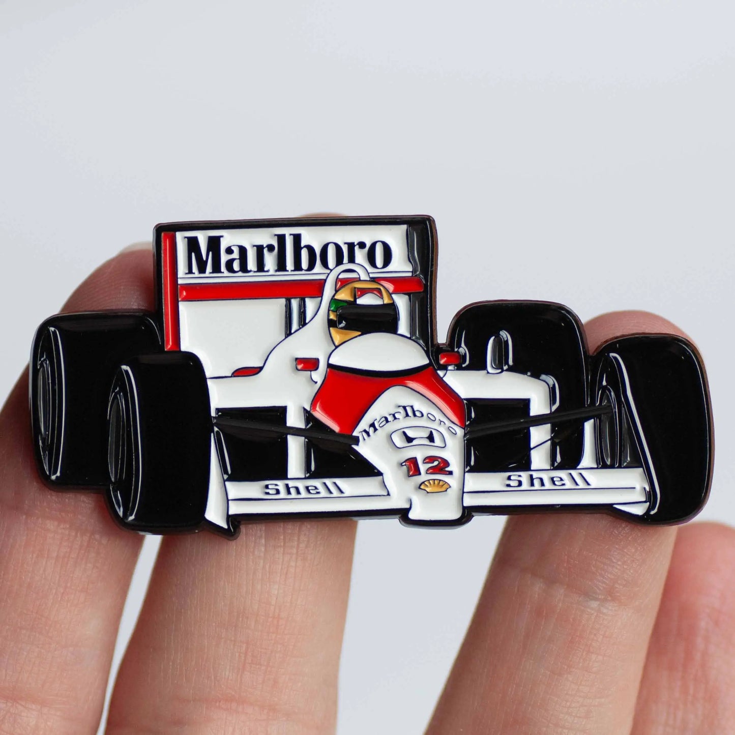 Ayrton Senna's MP4/4 Formula One Car Enamel Pin shown on hand